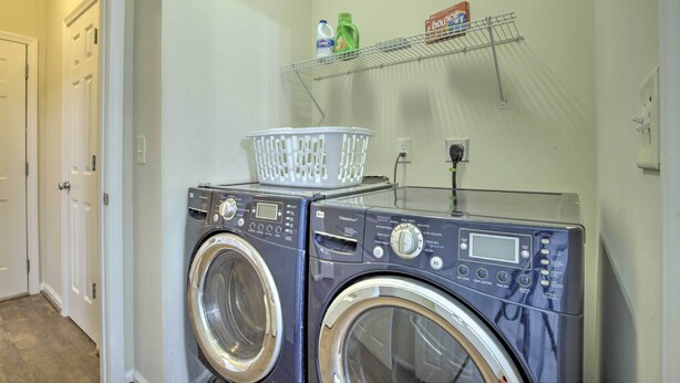 A laundry area with two front-loading washing machines, a basket on top, and a shelf with laundry supplies. - Modern Durham Retreat w/ Private Yard & Patio (Durham)