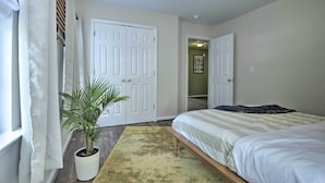 A bedroom with a bed, a potted plant, and a door leading to another room. - Modern Durham Retreat w/ Private Yard & Patio (Durham)