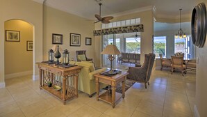 A spacious living room with a large window, a ceiling fan, and a dining area with chairs and a table. - Waterfront Cape Coral Home w/ Private Dock & Lanai (Cape Coral)