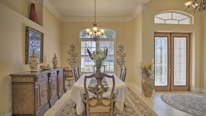 A dining area with a large table, chairs, a chandelier, and a decorative cabinet. - Waterfront Cape Coral Home w/ Private Dock & Lanai (Cape Coral)