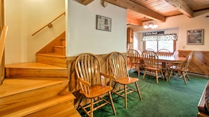 A wooden staircase leading to a dining area with a green carpet, wooden chairs, and a sign reading "Down White Heat". - Cozy Bartlett Townhome < 3 Mi to Attitash Mountain (Bartlett)