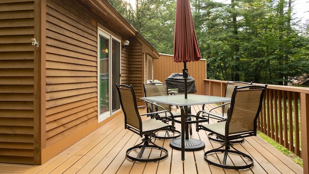 A wooden deck with a table and chairs, a covered grill, and a large umbrella. - Cozy Bartlett Townhome < 3 Mi to Attitash Mountain (Bartlett)
