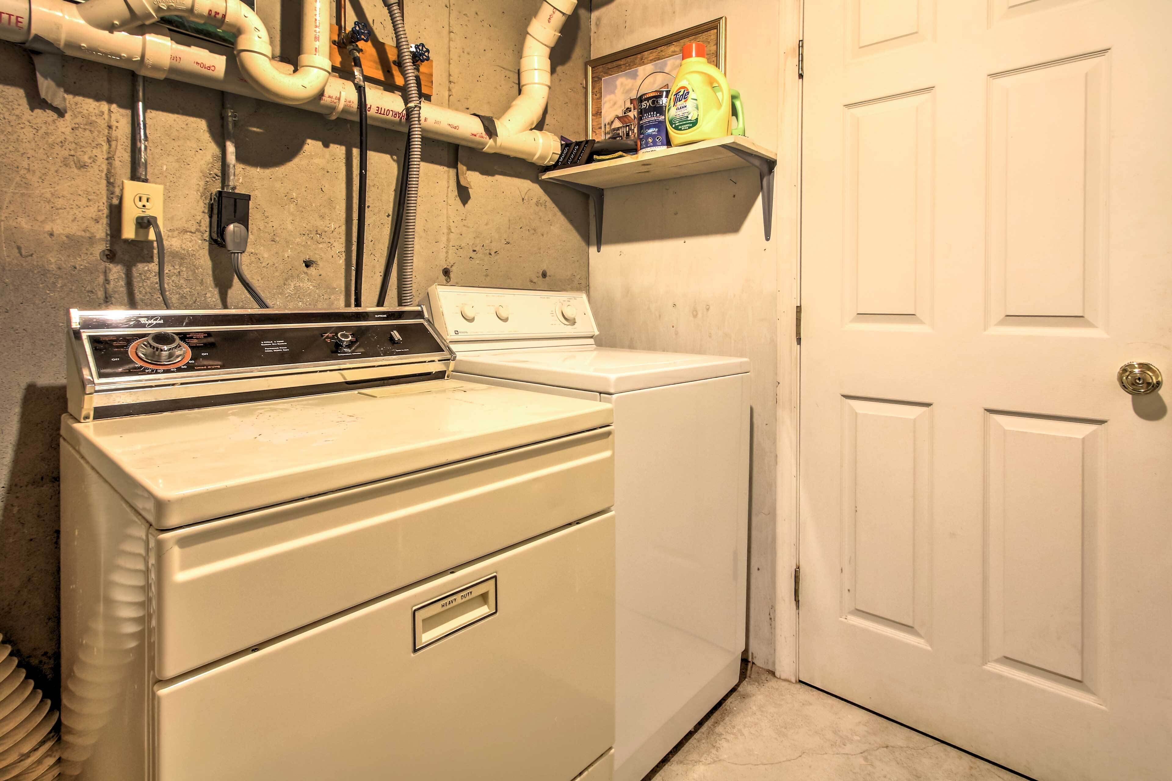 A laundry area with a washer and dryer, a shelf with cleaning supplies, and a door.