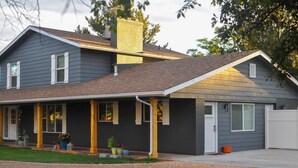 A two-story house with a covered porch, a chimney, and a garage. - Central Kanab Apartment w/ Updated Interior! (Kanab)