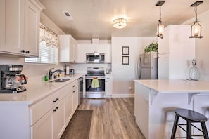 A kitchen with white cabinets, a microwave, an oven, a refrigerator, and a coffee maker.