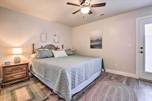 A bedroom with a bed, nightstand, lamp, and artwork on the walls.