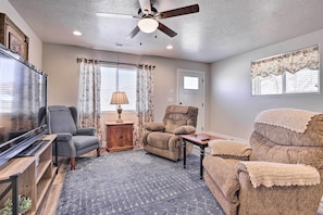 A living room with a ceiling fan, a flat-screen TV, a sofa, a recliner, and a patterned rug.