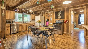 Eine rustikale Küche mit Holzbalken, einem Esstisch mit Stühlen, einem Kühlschrank, einer Mikrowelle und einem Waschbecken.