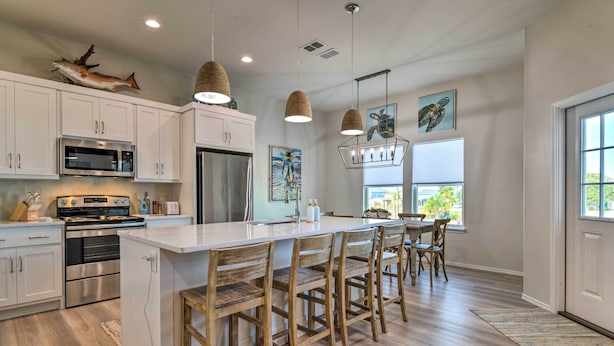 A modern kitchen with white cabinets, stainless steel appliances, and a large island with bar stools. - 6 Mi to Beach: Rockport Home w/ Pool Access! (Rockport)