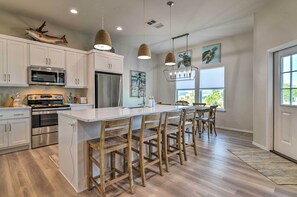 A modern kitchen with white cabinets, stainless steel appliances, and a large island with bar stools. - 6 Mi to Beach: Rockport Home w/ Pool Access! (Rockport)