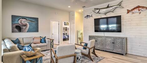 A living room with a sofa, armchairs, a TV, and wall-mounted fish decorations.