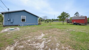 A blue building with a small porch and a red barn in the background.
