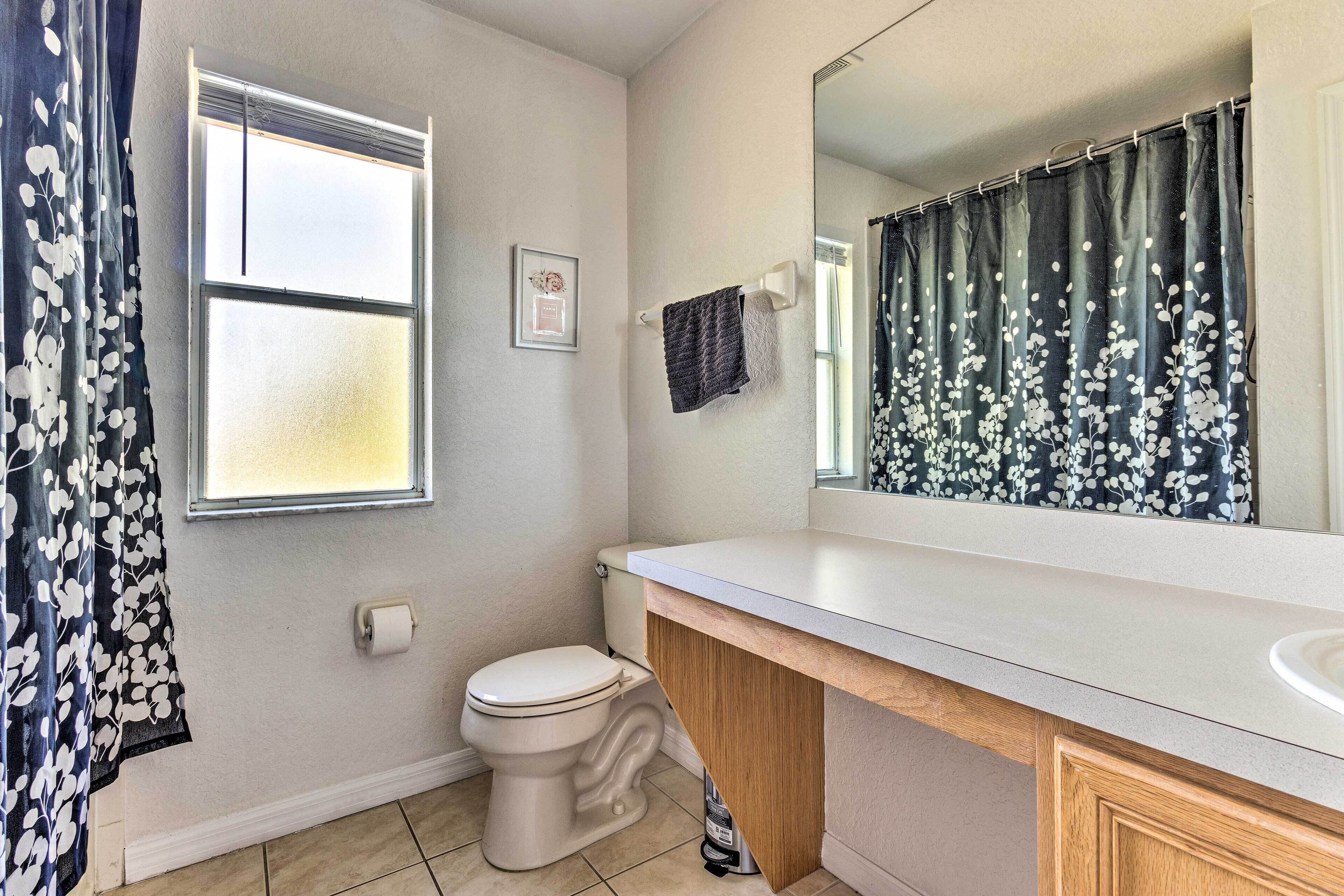 A bathroom with a toilet, a sink, a mirror, and a shower curtain.