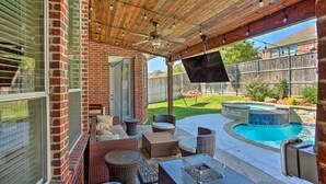 A covered patio with wicker furniture, a pool, and a TV screen. - Private Pool & Hot Tub: Spacious Murphy Getaway (Plano)