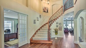A spacious foyer with a wooden staircase, a large rug, and a potted plant. - Private Pool & Hot Tub: Spacious Murphy Getaway (Plano)