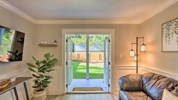 Een woonkamer met een leren bank, een houten salontafel, een potplant, een televisie en een deur die uitkomt op een achtertuin.