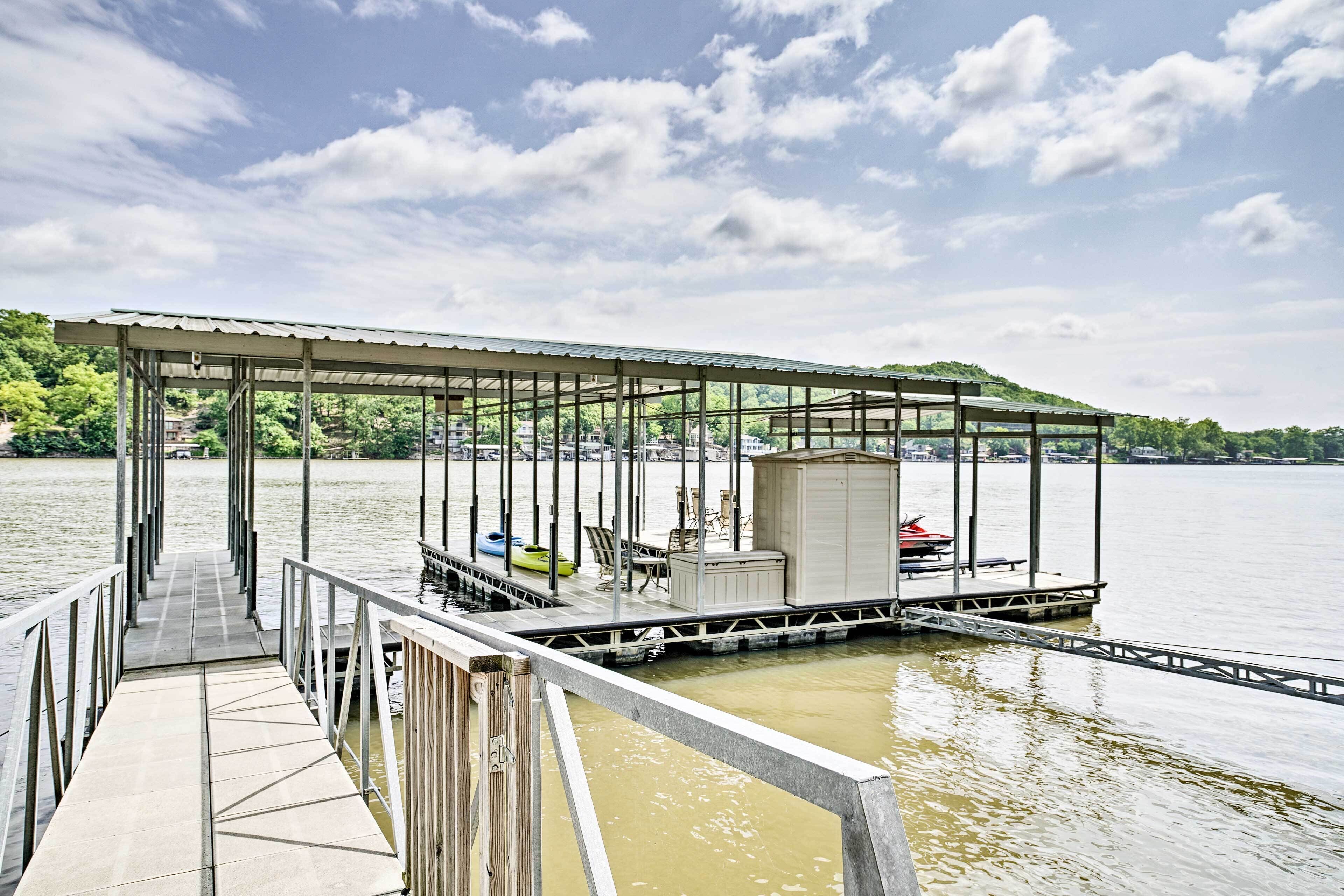 Un muelle techado con una zona de estar y un cobertizo pequeño, con vista a una masa de agua tranquila.
