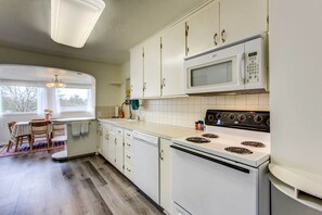 A kitchen with white cabinets, a microwave, a stove, and a dishwasher. - Charming Eugene Vacation Rental - 3 Mi to Downtown (Eugene)