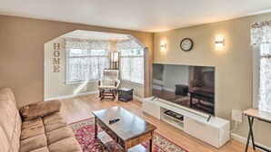 A living room with a sofa, a coffee table, a TV, and a chair. - Historic Meredith Home: Walk to Town Center! (Meredith)