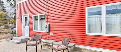A red house with two wicker chairs and a small table outside.