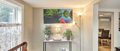 A room with a wooden bench, a table with a lamp, and a painting on the wall.