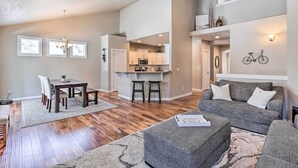 A spacious living area with a dining table, grey sofa, and a kitchen in the background. - Modern Bend Home ~ 3 Mi to Old Mill District! (Bend)