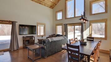A spacious living room with a large sofa, a dining table, and multiple windows.