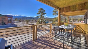 A wooden deck with a table and chairs, overlooking a mountainous landscape. - Woodland Park Escape: Licensed, Hot Tub, Mtn Views (Woodland Park)