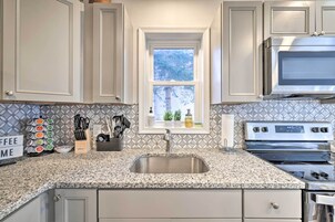 Una cocina con encimeras de granito, electrodomésticos de acero inoxidable y una ventana con vista a árboles.