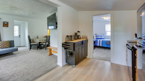 Um apartamento moderno com cozinha, mesa de jantar com cadeiras, sofá e cama.