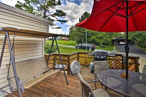 Relax on the deck with a metal table, chairs, and a swing set, perfect for outdoor dining and leisure.
