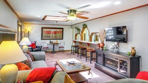A living room with a ceiling fan, a television, a fireplace, and a dining area with a table and chairs. - Bull Shoals Lake Home at Beaver Creek Marina! (Kissee Mills)