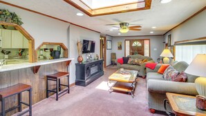 A spacious living area with a high ceiling, a ceiling fan, a kitchen area with a wooden countertop, and a cozy seating arrangement with a sofa and a coffee table. - Bull Shoals Lake Home at Beaver Creek Marina! (Kissee Mills)
