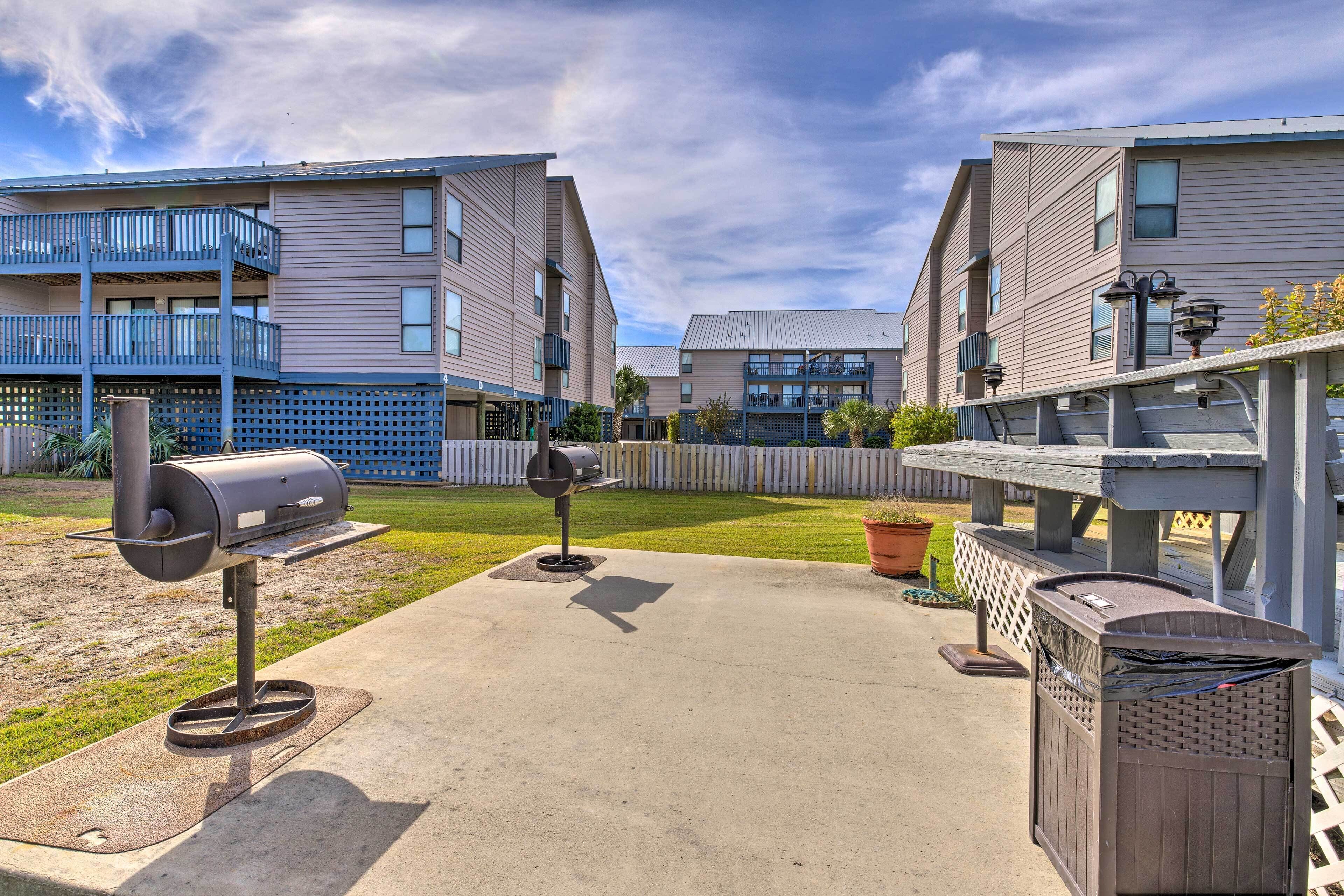 Un edificio residencial con patio que incluye asadores al aire libre y un contenedor de basura.