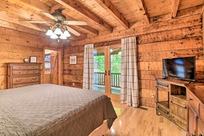 Relax in a serene bedroom with a large bed, ceiling fan, and sliding door to an outdoor area with a view of lush greenery.