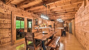Interior de madera con comedor, cocina y un amplio ventanal corredera que da a un espacio exterior.