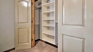 Ein begehbarer Kleiderschrank mit geöffneten Türen, der Regale und Kleiderstangen zeigt.