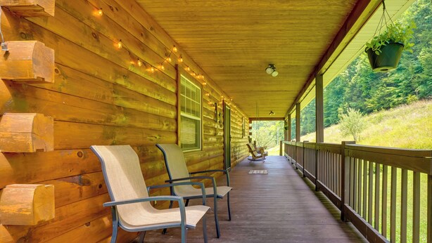 A wooden cabin with a covered porch, chairs, and a hanging plant. - Serene Mountain Retreat on 40 Acres w/ Fire Pit! (Bomont)