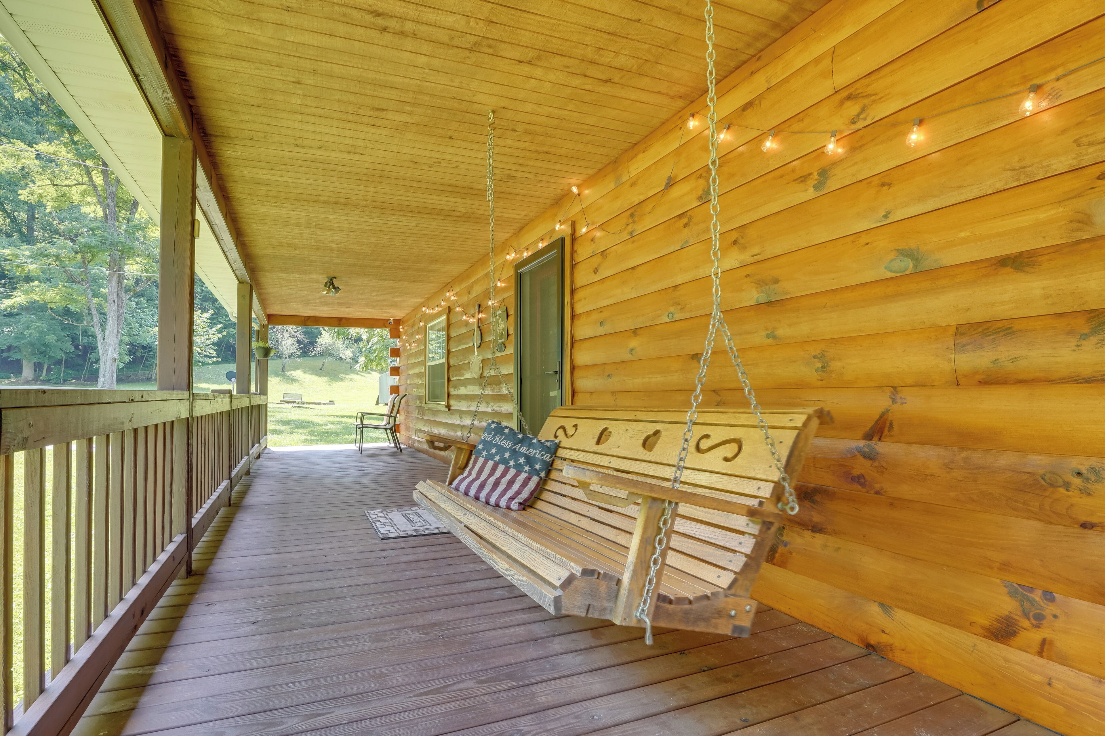 A wooden porch with a swing seat and a bench, featuring a view of the outdoors.