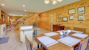 A wooden cabin interior with a dining area, kitchen, and staircase. - Serene Mountain Retreat on 40 Acres w/ Fire Pit! (Bomont)