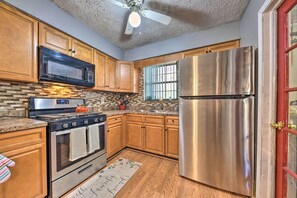 A kitchen with wooden cabinets, a stainless steel refrigerator, a microwave, a stove, and a ceiling fan. - Cozy Jacksonville Home w/ Yard ~ 8 Mi to Dtwn (Jacksonville)