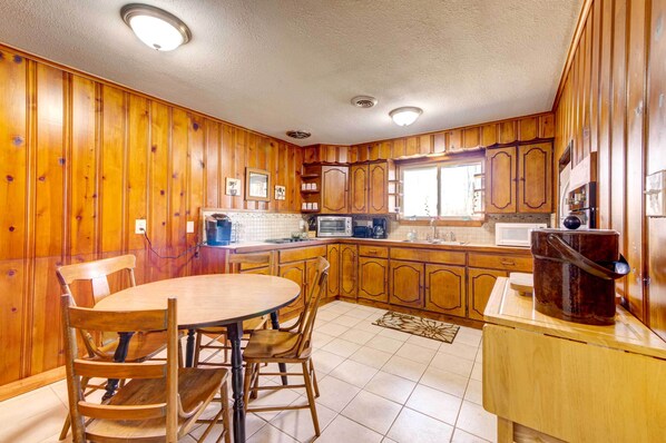 A kitchen with wooden cabinets, a dining table with chairs, and a refrigerator. - Pet-friendly Youngstown Cottage w/ Yard (Poland)