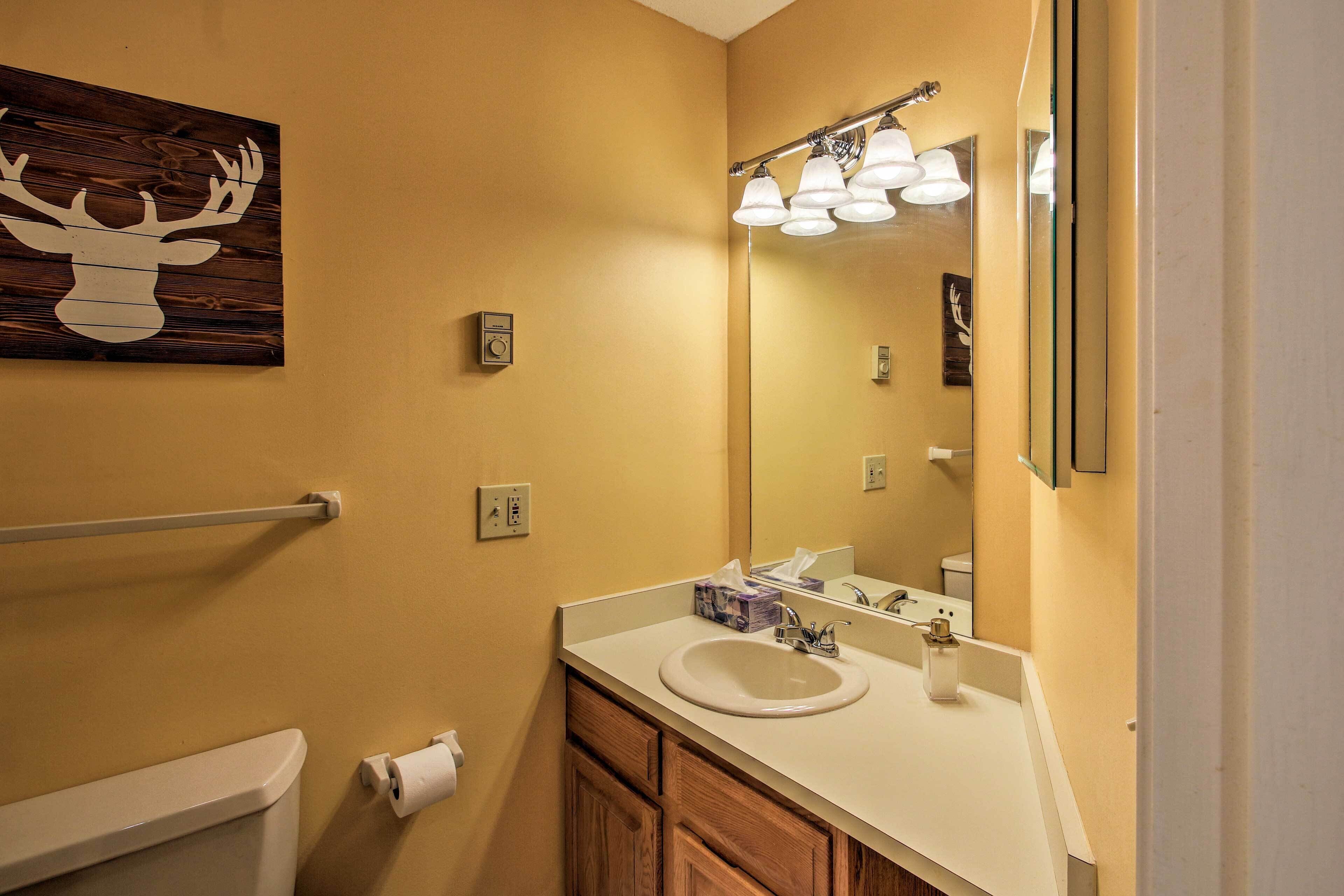 A bathroom with a wooden deer head artwork, a white sink, a mirror, and a towel rack.
