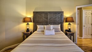 Quarto com uma cama grande, duas mesas de cabeceira com luminárias e um painel de cabeceira de madeira.