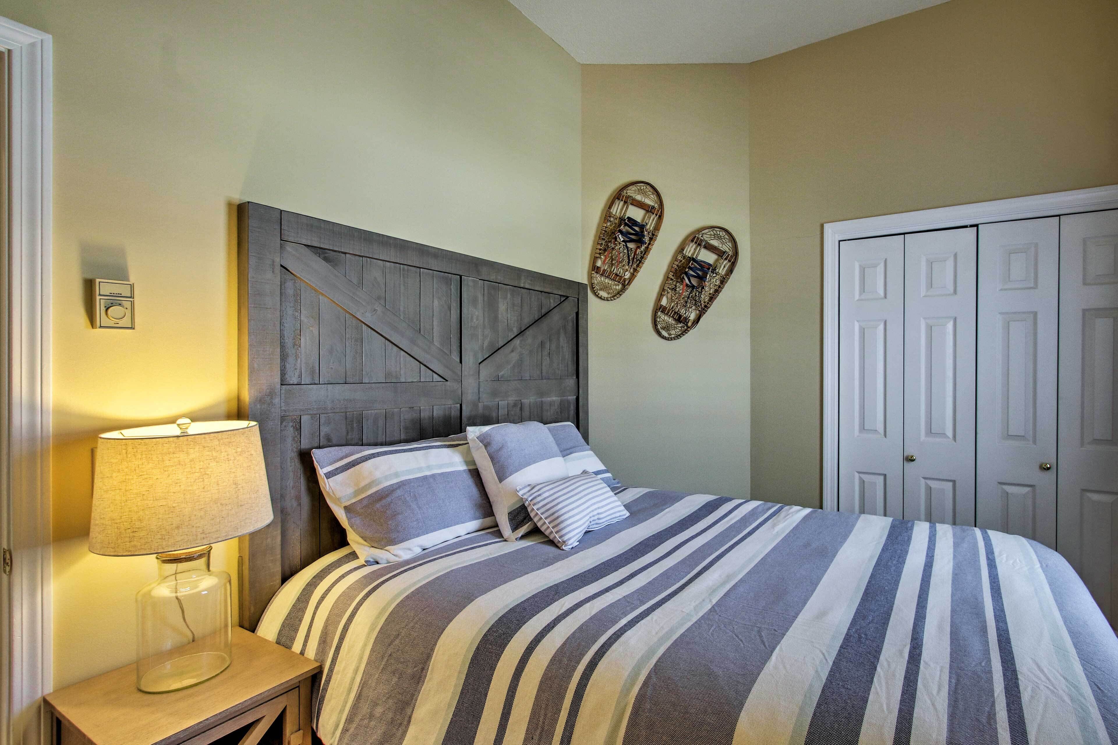 A bedroom with a bed, a nightstand, a lamp, a wall-mounted shelf, and a wardrobe.