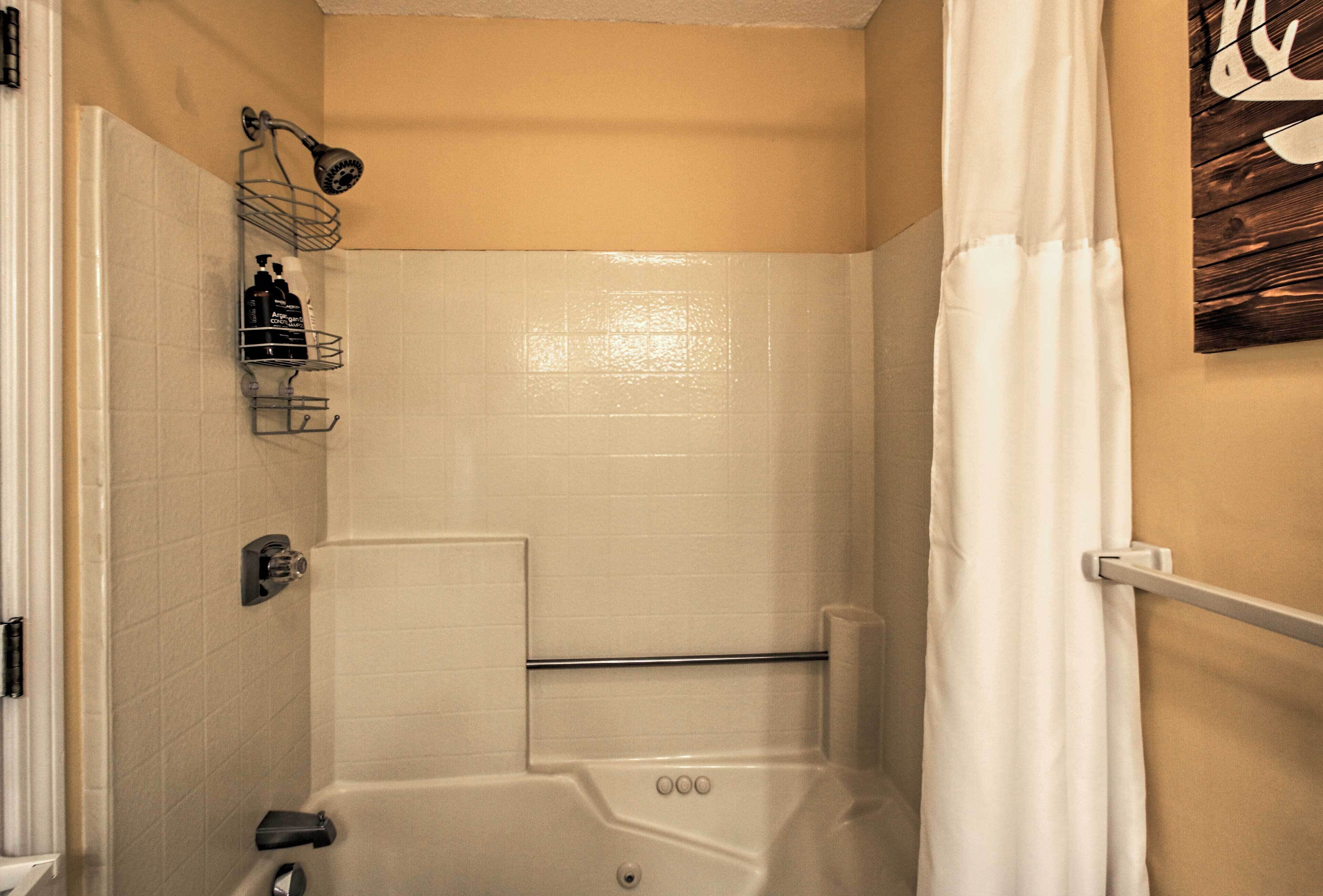 A bathroom with a bathtub, a shower, and a towel rack.