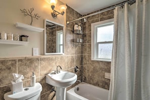 Ein Badezimmer mit Badewanne, Waschbecken, Toilette, Dusche und einem Fenster.