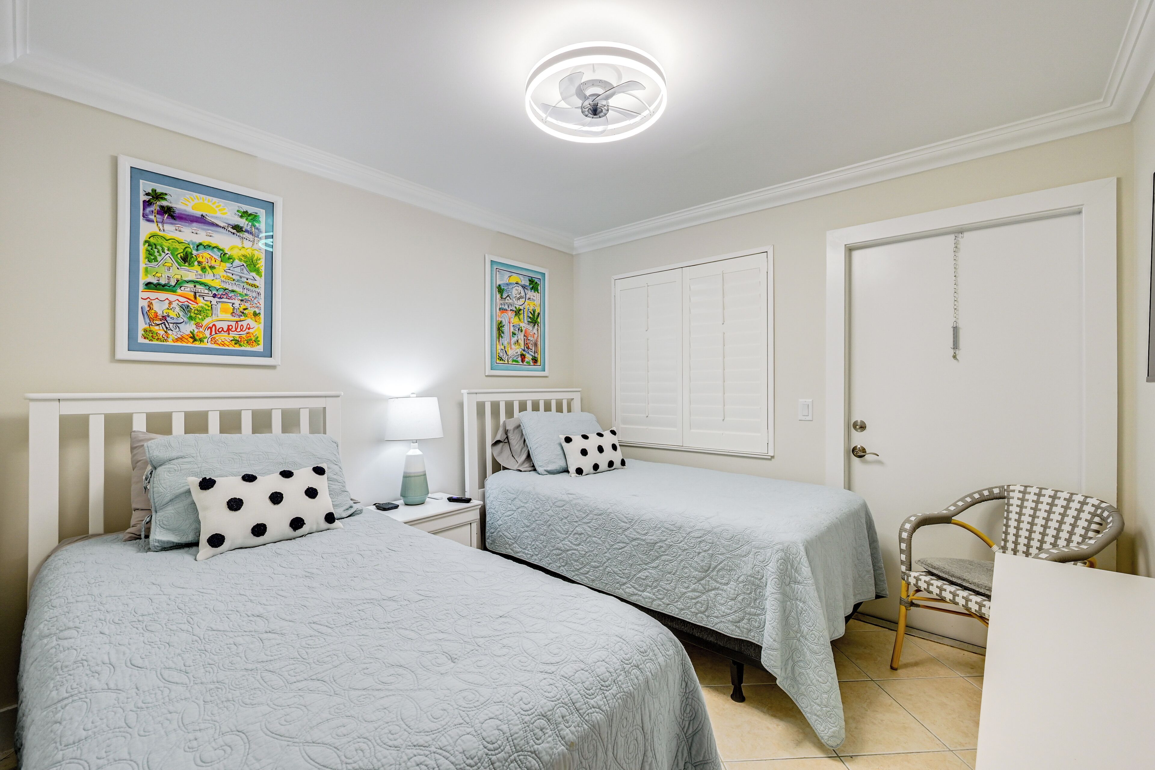 Un dormitorio con dos camas, una silla y una puerta.
