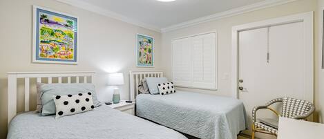 Un dormitorio con dos camas, una silla y una puerta.