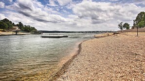 A pebbled beach with a dock extending into calm water, surrounded by trees and a cloudy sky. - Walk to Boat Ramp! Lakefront Home w/ Deck in Afton (Afton)
